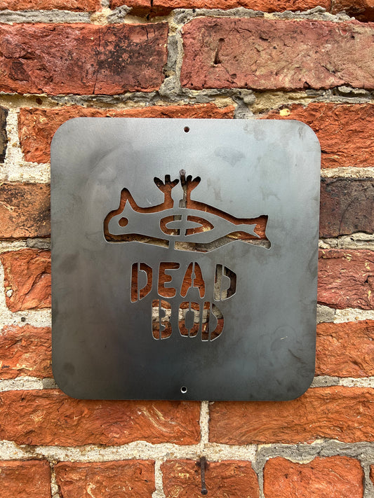 Metal sign with dead bird design and 'DEAD Bod' text on a brick wall.