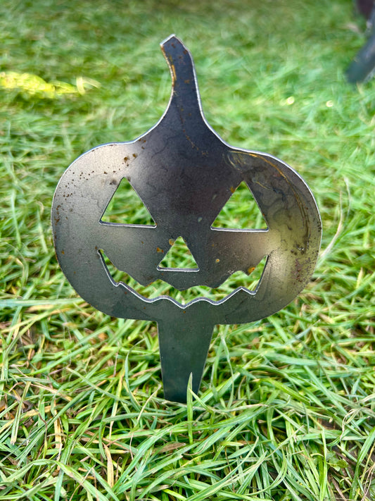 Metal pumpkin-shaped decorative stake on grass