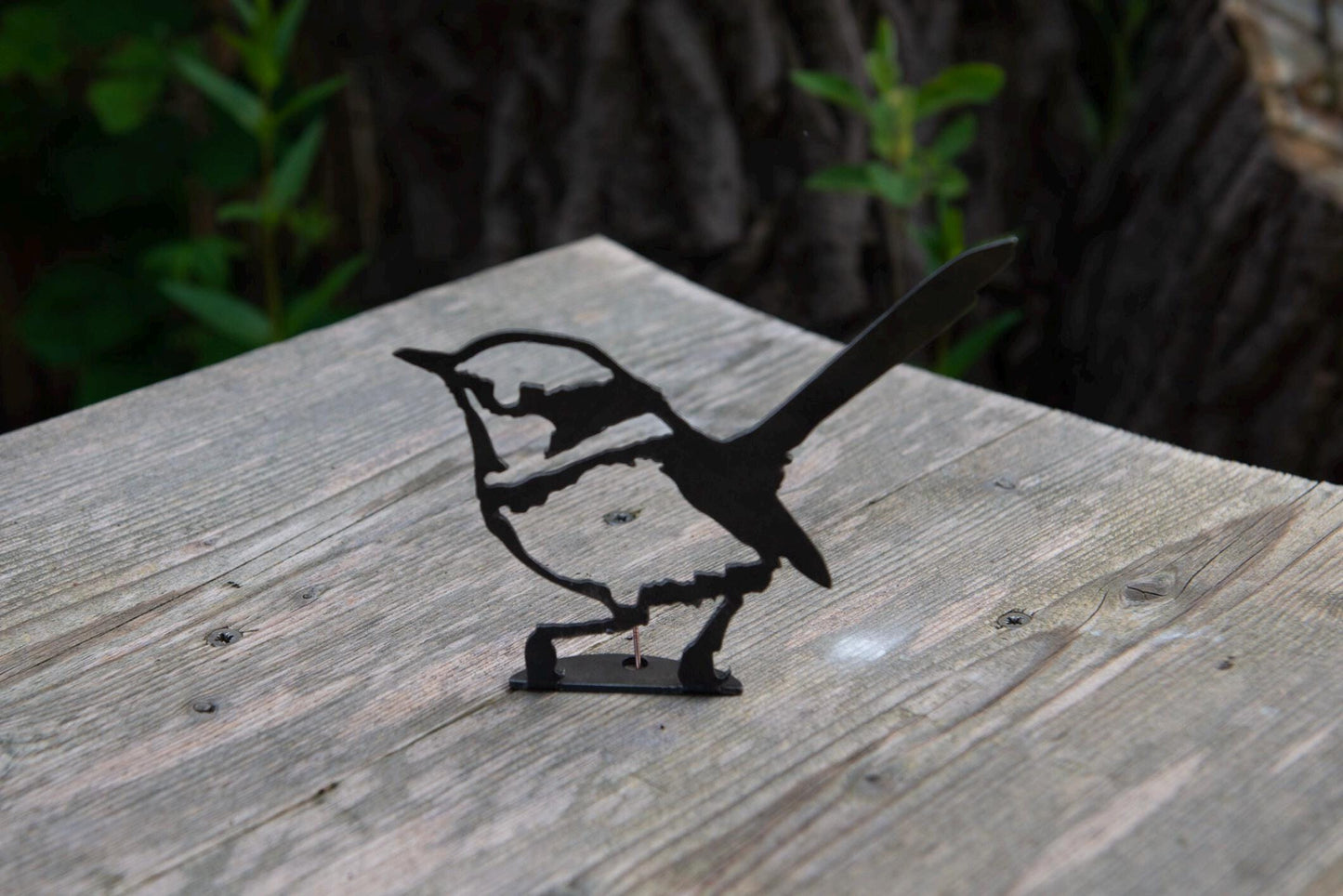 Steel garden ornament of a European Wren sat on a wooden ledge
