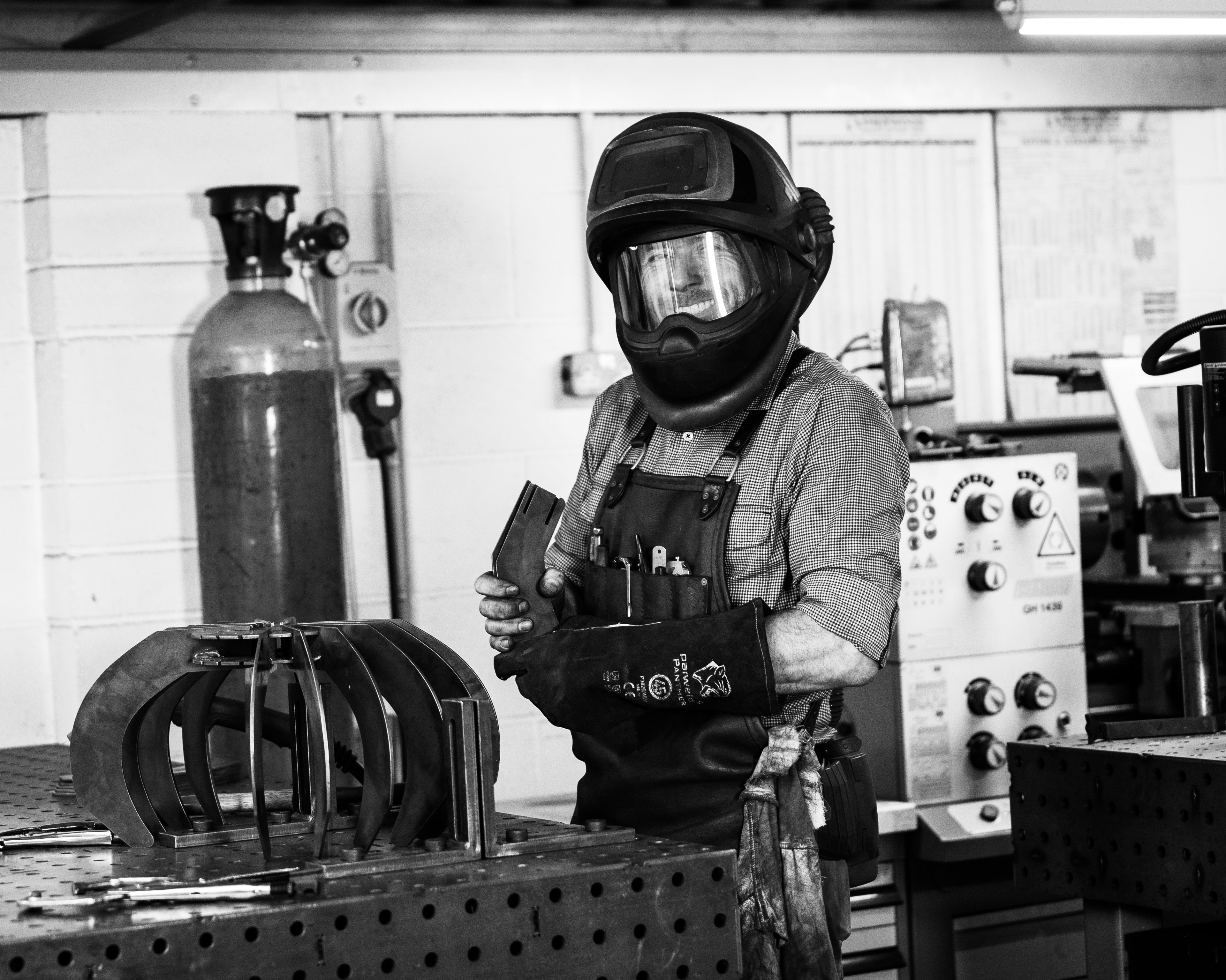Photo of Tim wearing a welding helmet in his workshop