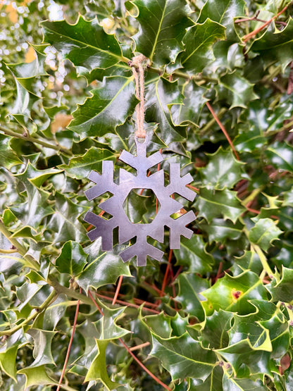 Metal snowflake decoration hanging on green holly leaves