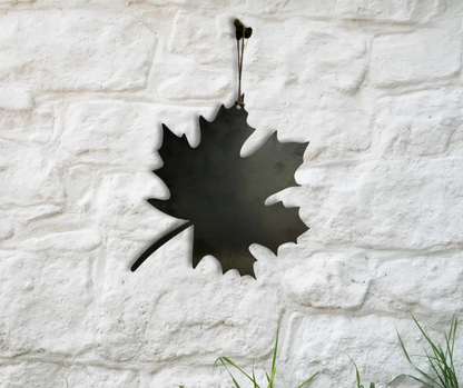 Decorative metal maple leaf ornament on white brick wall