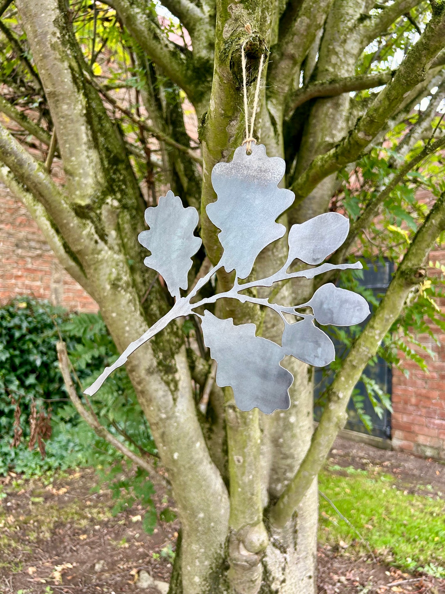 Decorative metal oak leaf ornament hanging from a tree