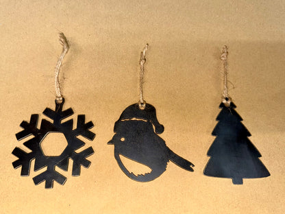 Three black Christmas-themed decorations, snowflake, Robin and Christmas Tree on a beige background