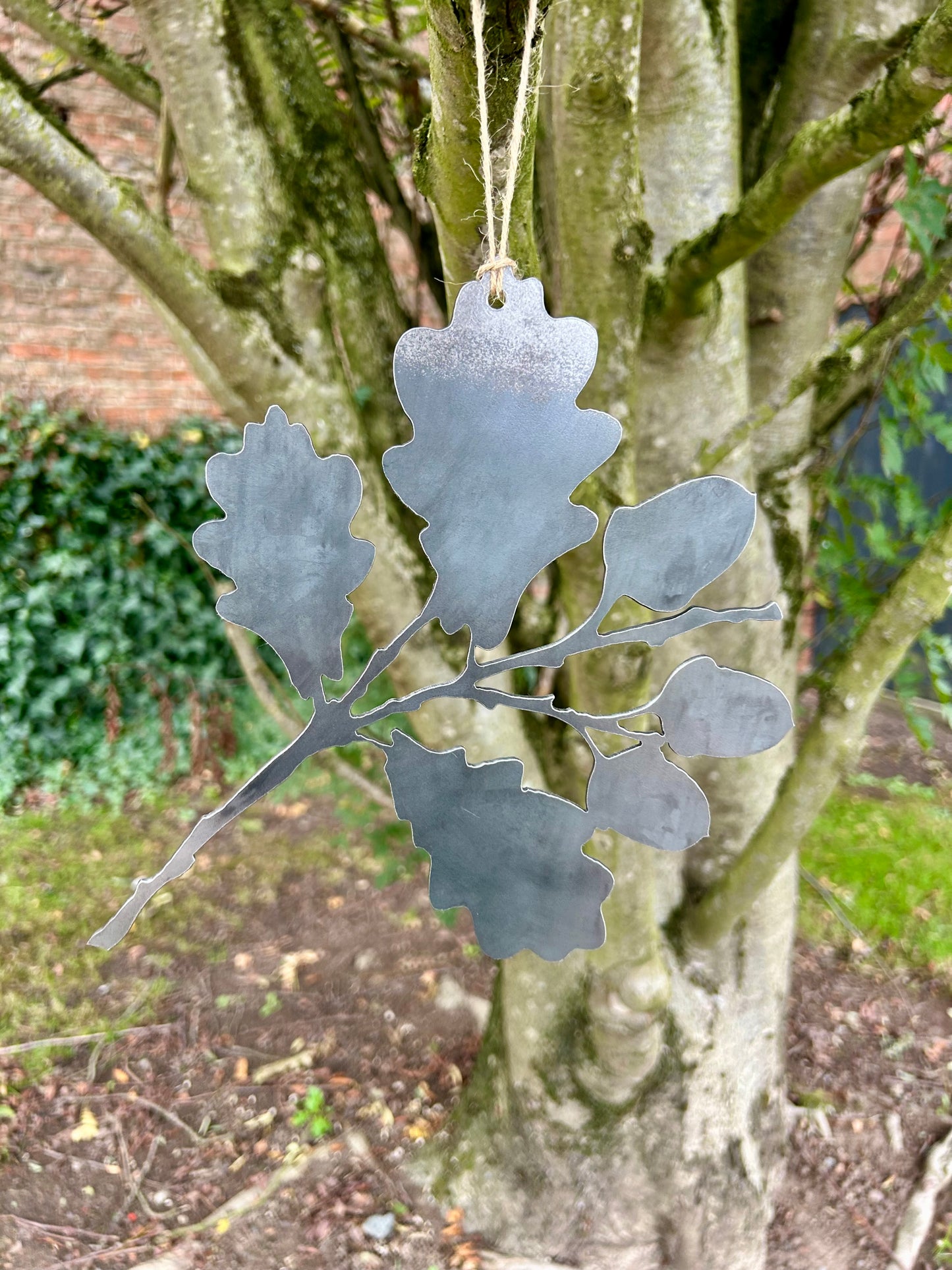 Decorative metal oak leaf ornament hanging from a tree