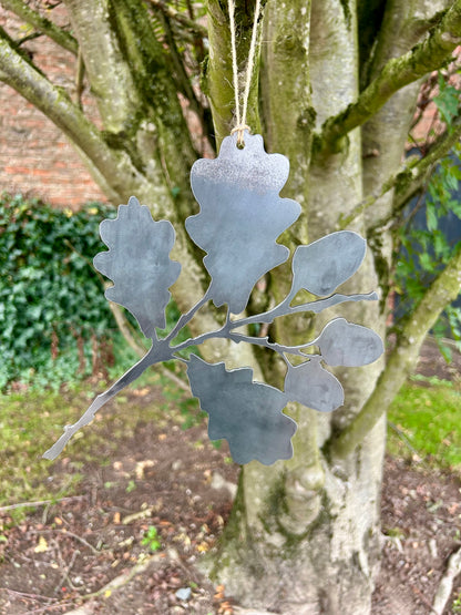 Decorative metal oak leaf ornament hanging from a tree
