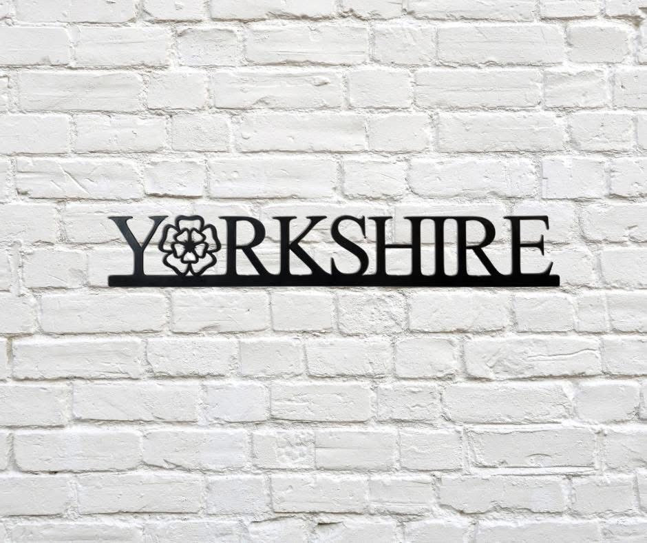 Decorative metal sign with 'Yorkshire' on a white brick wall