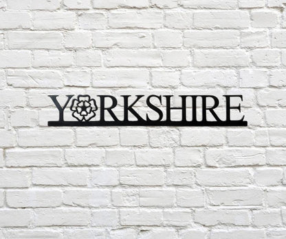 Decorative metal sign with 'Yorkshire' on a white brick wall
