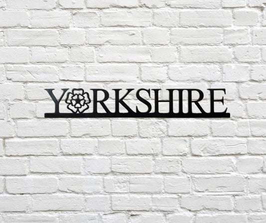 Decorative metal sign with 'Yorkshire' on a white brick wall