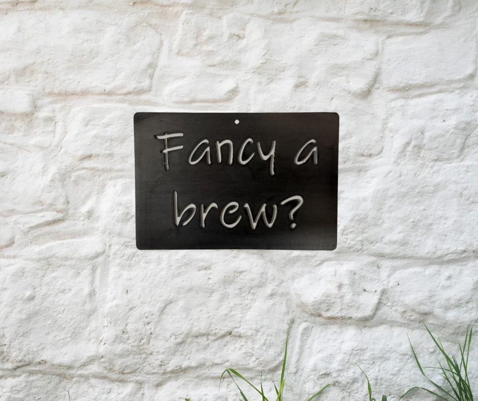 Metal sign with 'Fancy a brew?' text on a white stone wall.