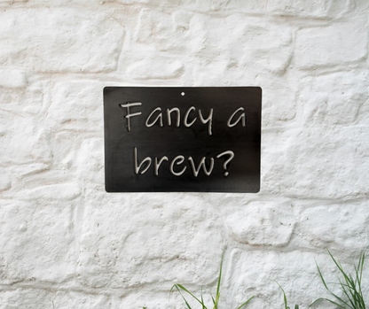 Metal sign with 'Fancy a brew?' text on a white stone wall.
