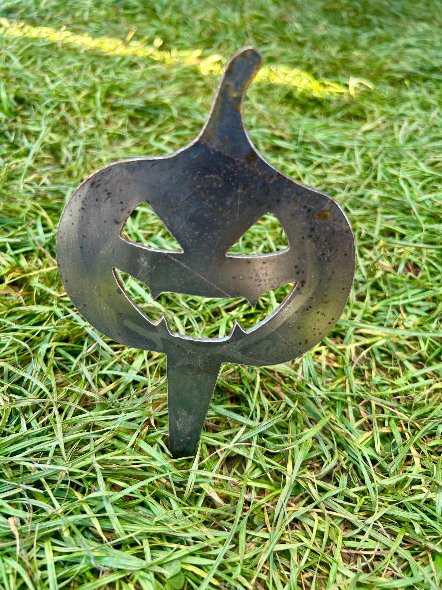 Metal pumpkin-shaped decorative stake on grass