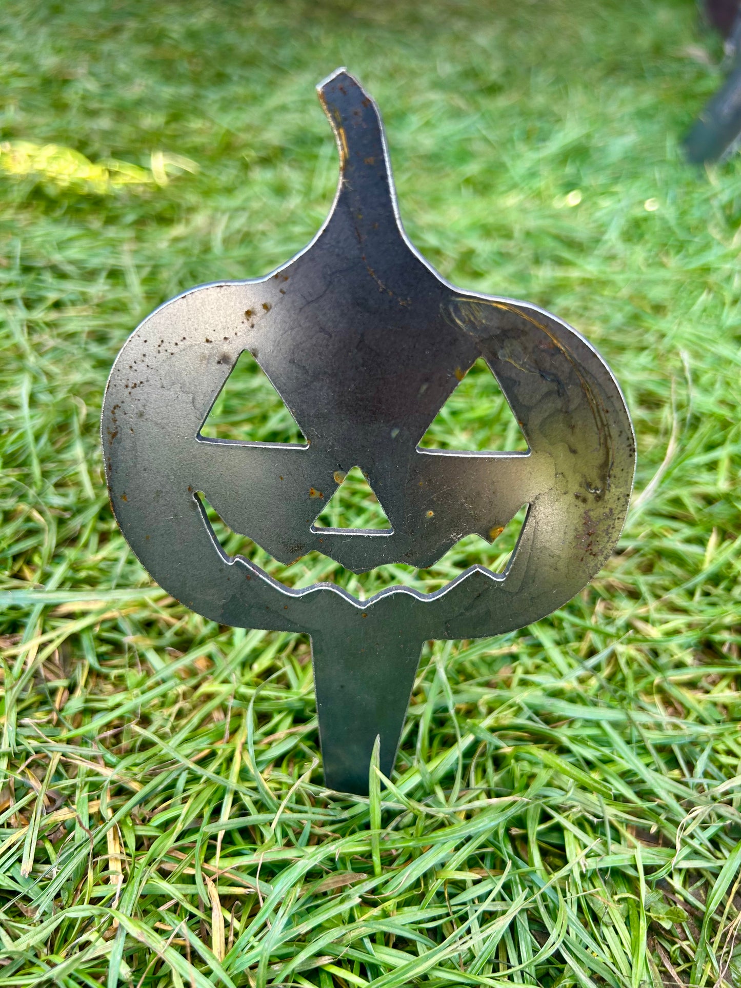 Metal pumpkin-shaped decorative stake on grass