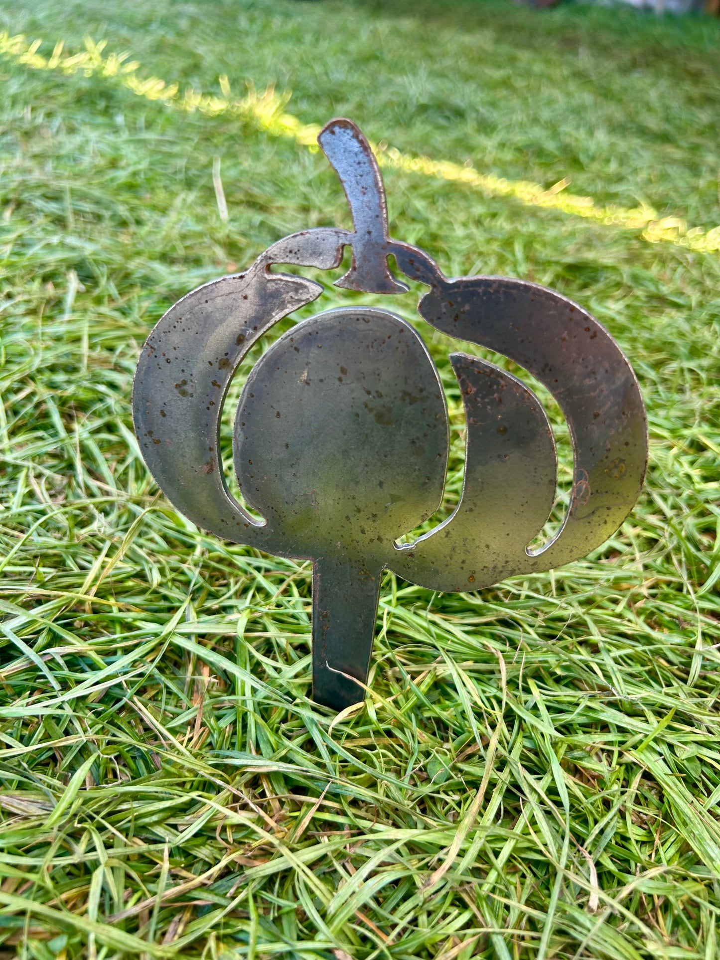 Metal pumpkin-shaped decorative stake on grass