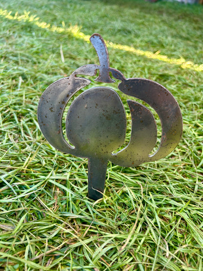 Metal pumpkin-shaped decorative stake on grass