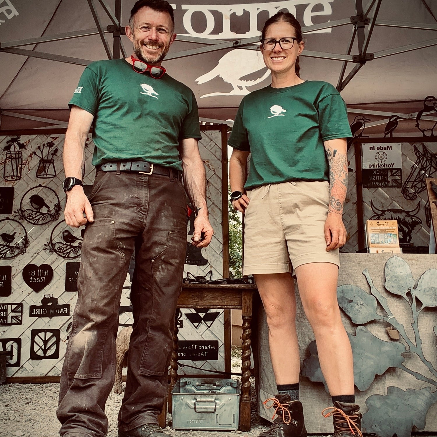 Tim and Nicki wearing green shirts with a logo, standing under a tent with 'Forme' branding.