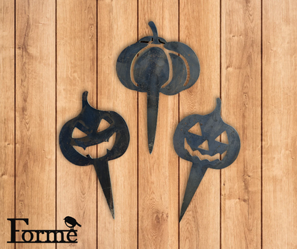 Three black metal pumpkin decorations on a wooden background with 'Forme' branding.