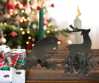 Decorative candle holders shaped like a Rpbin and a reindeer on a wooden surface with a Christmas tree in the background.