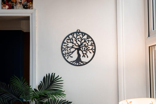 A steel tree of life wall art mounted on a wall, with a dark and textured surface, likely representing rust.